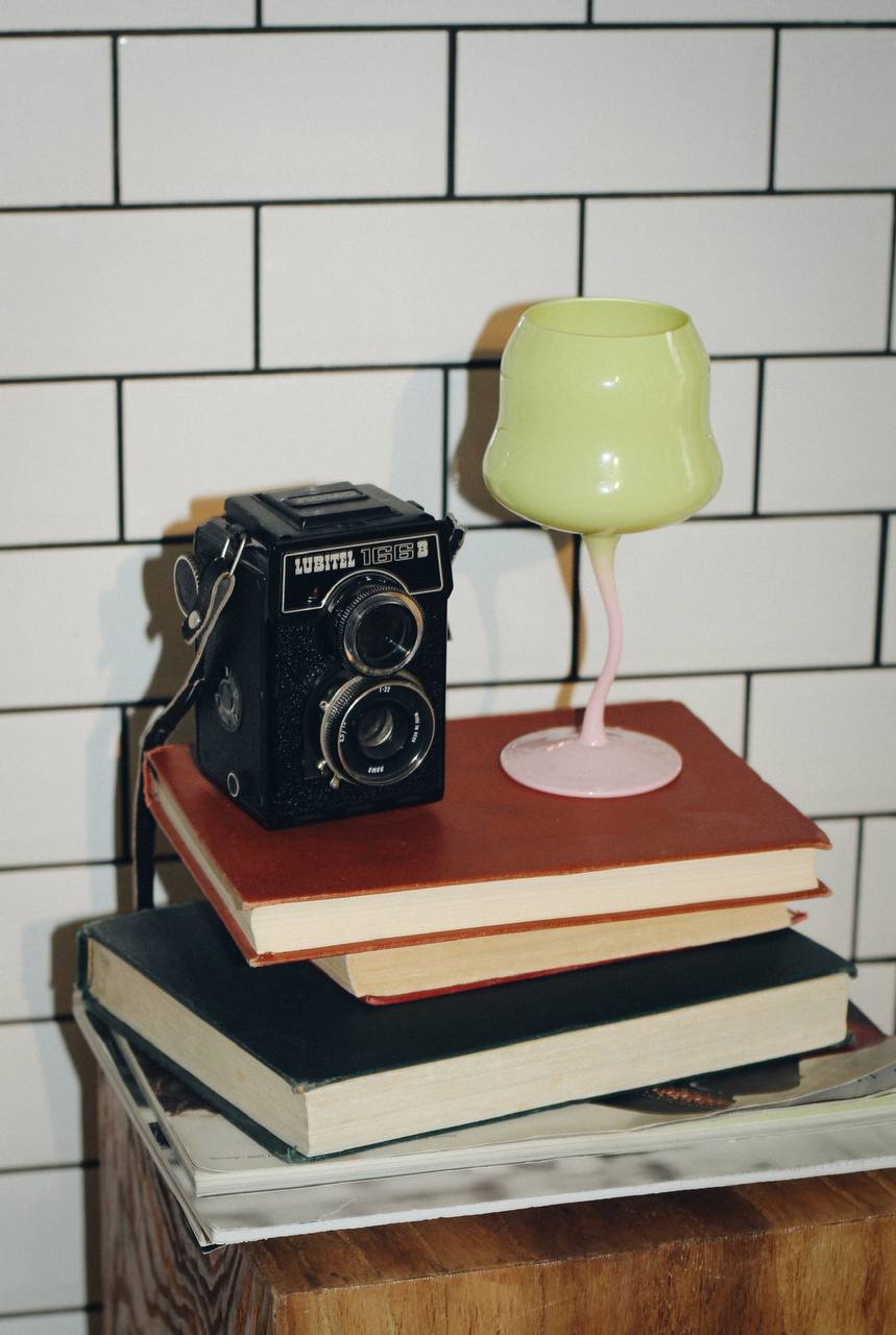 Vintage camera and pastel glass styled on stacked books for the décor brand